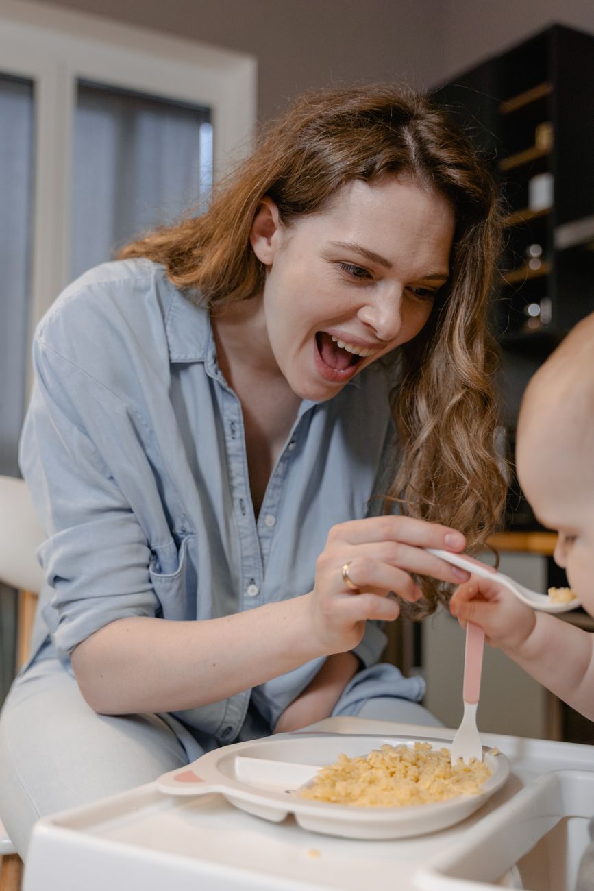 Mamá feliz dándole de comer a su bebé
